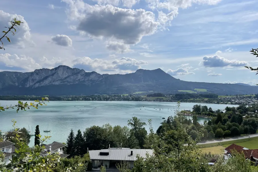 Aerial view of a turquoise mountain lake with lush green forested slopes